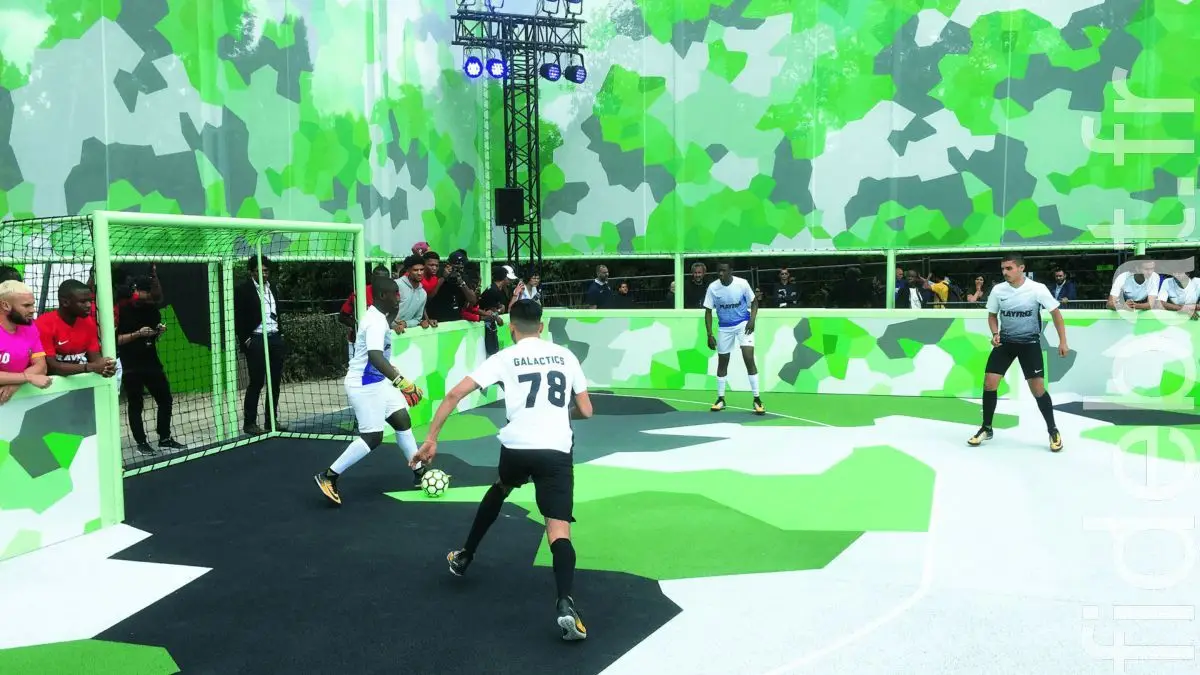 Match de foot à 5 sur un City Five SAE aux murs camouflage vert, avec joueurs en action devant les buts
